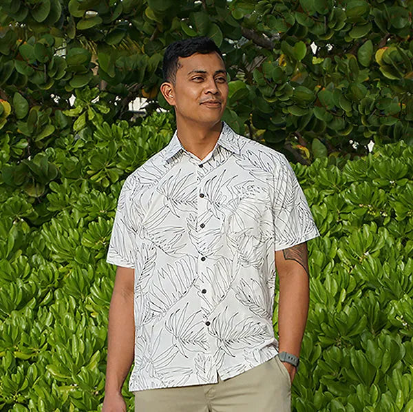 Men's white Hawaiian aloha button down shirt. The shirt has a palm leaf design, and Hawaiian kapa motif on the collar.